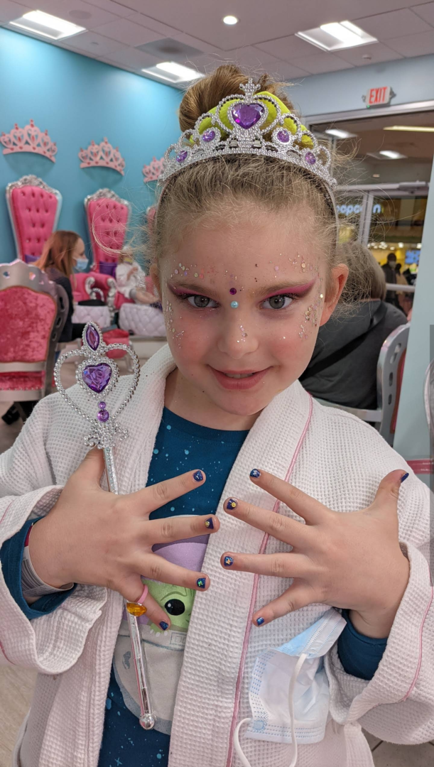 A little girl with her hands and face painted.